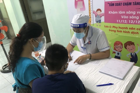Bác sỹ thăm khám cho trẻ em đến khám. (Ảnh: PV/Vietnam+)