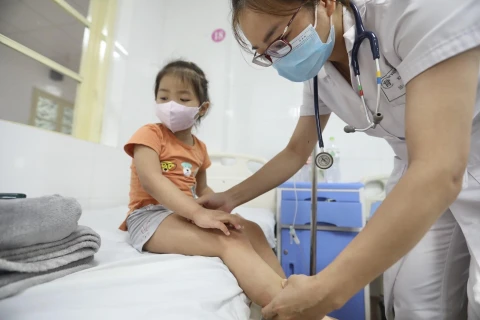 Bác sỹ khám cho bệnh nhi sốt xuất huyết tại bệnh viện Thanh Nhàn. (Ảnh: Minh Quyết/TTXVN)