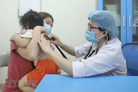 Bác sỹ Bệnh viện Bệnh nhiệt đới Trung ương khám cho bệnh nhi xuất hiện triệu chứng cúm A. (Ảnh: Minh Quyết/TTXVN)
