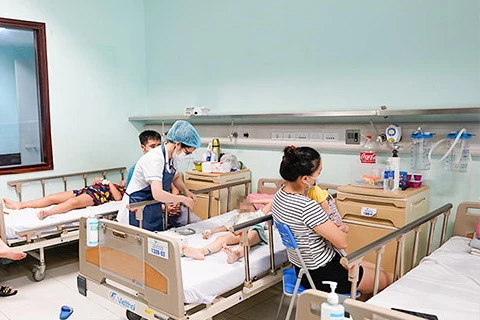 Nhân viên y tế chăm sóc cho trẻ mắc virus Adeno. (Ảnh: PV/Vietnam+)