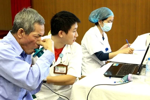 Nhân viên y tế khám, đo chức năng hô hấp cho người bệnh. (Ảnh: TTXVN/Vietnam+)