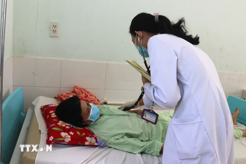 Bác sỹ Bệnh viện Đa khoa tỉnh Vĩnh Long thăm khám cho bệnh nhân sốt xuất huyết. (Ảnh: Lê Thúy Hằng/TTXVN)
