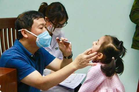 Chuyên gia khám cho các em nhỏ bị dị tật bẩm sinh phức tạp vùng hàm mặt. (Ảnh: PV/Vietnam+)