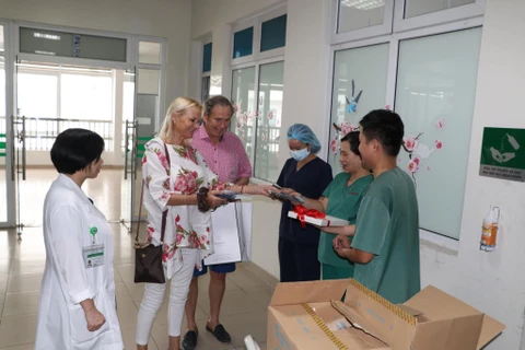 Cặp vợ chồng người Anh xúc động và vui mừng khi được gặp và tặng sách cho các y bác sỹ. (Ảnh: PV/Vietnam+)