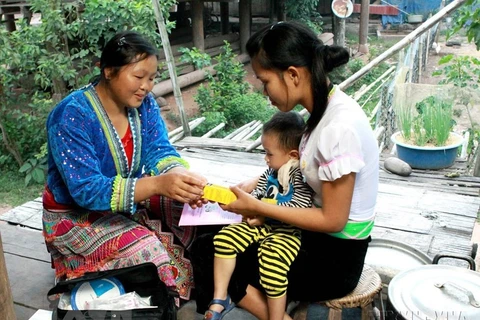 Cô đỡ thôn bản chăm sóc sức khoẻ bà mẹ, trẻ em tại huyện Mường Nhé (Điện Biên). (Ảnh: Dương Ngọc/TTXVN)