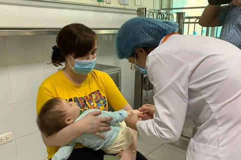 Bác sỹ kiểm tra sức khoẻ cho trẻ mắc bệnh tay chân miệng tại Bệnh viện Nhi Trung ương. (Ảnh: PV/Vietnam+)