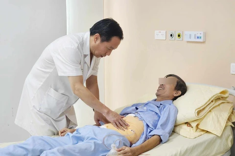 Phó giáo sư Nguyễn Anh Tuấn khám cho bệnh nhân sau phẫu thuật. (Ảnh: PV/Vietnam+)