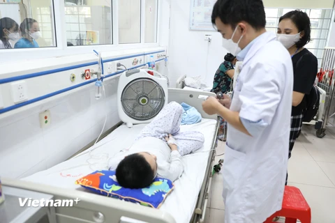 Bác sỹ theo dõi sức khỏe cho một bệnh nhi. (Ảnh: Minh Quyết/Vietnam+)