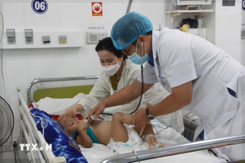 Bác sỹ Bệnh viện Bệnh viện Bệnh Nhiệt đới tỉnh Khánh Hòa thăm khám cho bệnh nhi mắc tay chân miệng. (Ảnh: Phan Sáu/TTXVN)