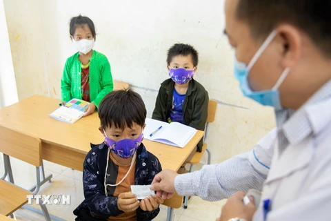 Cán bộ y tế phát thuốc cho các em học sinh phòng chống bệnh bạch hầu. (Ảnh: Nam Thái/TTXVN)