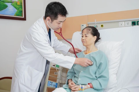Tiến sỹ Đặng Quang Huy - Phó giám đốc Trung tâm và Ekip gây mê phẫu thuật thuộc Trung tâm Tim mạch khám cho bệnh nhân. (Ảnh: PV/Vietnam+)
