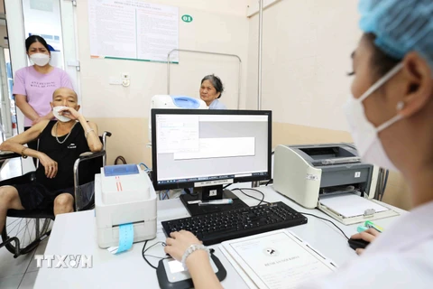 Nhân viên y tế hoàn thiện các thủ tục khám chữa bệnh cho bệnh nhân. (Ảnh: Minh Quyết/Vietnam+)