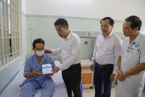 Tổng Giám đốc Bảo hiểm Xã hội Việt Nam Nguyễn Thế Mạnh tặng thẻ Bảo hiểm Y tế cho người dân. (Ảnh: PV/Vietnam+)