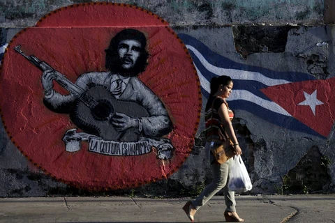 Một phụ nữ đi bức graffiti của Che Guevara và lá cờ Cuba trên đường phố thủ đô La Habana. (Nguồn: Reuters)