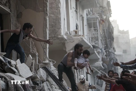 Nhân viên cứu hộ chuyển em bé ra khỏi tòa nhà đổ nát sau các cuộc không kích tại thành phố Aleppo. (Nguồn: AFP/TTXVN)