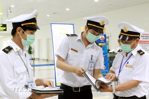 Nhân viên Trung tâm kiểm dịch y tế quốc tế-Sân bay quốc tế Nội Bài chuẩn bị phát tờ khai y tế cho hành khách đến từ vùng có dịch. (Ảnh: Dương Ngọc/TTXVN)