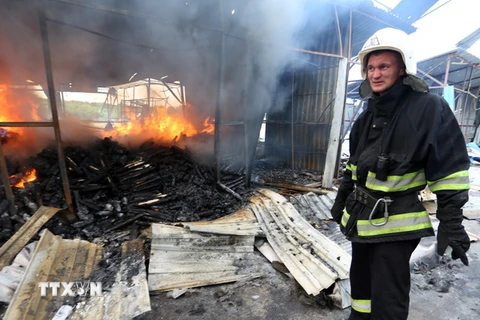 Lính cứu hỏa dập lửa đám cháy khu chợ ở Donetsk sau vụ pháo kích. (Nguồn: AFP/ TTXVN)