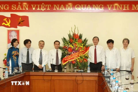Trưởng Ban Tuyên giáo Trung ương Đinh Thế Huynh tặng lẵng hoa chúc mừng TTXVN. (Ảnh: Minh Quyết/TTXVN)
