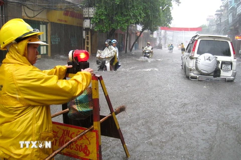 Công ty thoát nước Hà Nội cắm biển cảnh báo điểm nguy hiểm trên tuyến đường bị ngập lụt. (Ảnh: Nhật Anh/TTXVN)