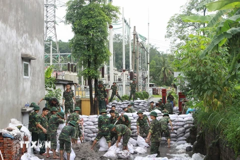 Lực lượng quân đội tham gia đóng cát vào bao tải, đắp đê ngăn bùn và đất đá tràn vào trạm biến thế điện. (Ảnh: Minh Quyết/TTXVN)