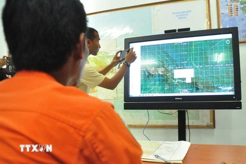 Nhân viên Cơ quan tìm kiếm và cứu nạn quốc gia Indonesia theo dõi địa hình khu vực ở Jayapura trên bản đồ nhằm tìm kiếm máy bay mất tích. (Nguồn: AFP/TTXVN)