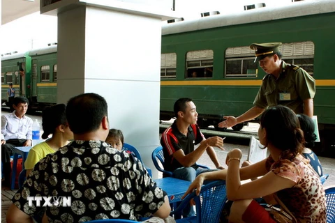 Cán bộ Ga Hà Nội nhắc nhở hành khách hút thuốc đúng nơi quy định. (Ảnh: Dương Ngọc/TTXVN)