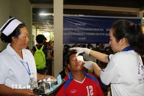 Bác sỹ Việt Nam và Lào đang tiến hành kiểm tra, mở băng mắt cho một bệnh nhân sau khi mổ. (Ảnh: Phạm Kiên/TTXVN)