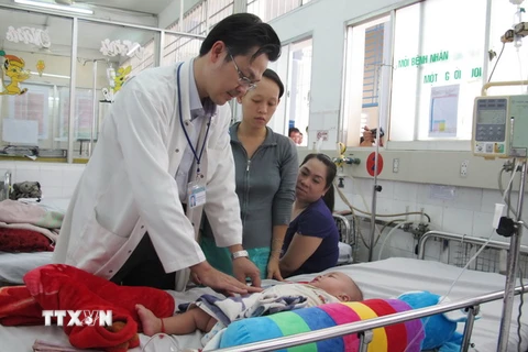 Bác sỹ bệnh viện Nhi Đồng 1 thăm khám cho bệnh nhi bị sốt xuất huyết. (Ảnh: Phương Vy/TTXVN)