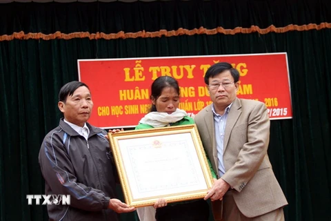 Ông Thái Huy Vinh (phải) trao Huân chương Dũng cảm của Chủ tịch nước cho đại diện gia đình em Nguyễn Anh Tuấn. (Ảnh: Tá Chuyên/TTXVN)