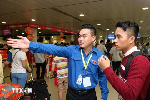 Thanh niên tình nguyện hướng dẫn hành khách đến khu vực làm thủ tục hàng không tại sân bay Tân Sơn Nhất. (Ảnh: Mạnh Linh/TTXVN)