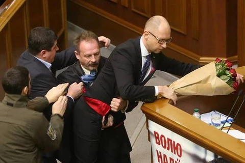 Ông Oleg Barna tặng một bó hoa rồi tìm cách bế Thủ tướng Arseny Yatsenyuk khỏi bục phát biểu trước Quốc hội. (Nguồn: kyivpost.com)