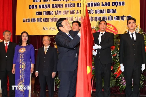 Chủ tịch nước Trương Tấn Sang gắn Danh hiệu Anh hùng Lao động lên lá cờ truyền thống của Trung tâm gây mê và hồi sức ngoại khoa, Bệnh viện hữu nghị Việt Đức. (Ảnh: Nguyễn Khang/TTXVN) 