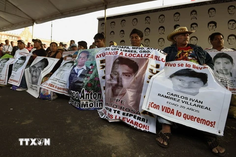 Thân nhân của các sinh viên mất tích tham gia cuộc biểu tình quy mô lớn tại thủ đô Mexico City kêu gọi chính quyền đẩy nhanh chiến dịch tìm kiếm. (Nguồn: AFP/TTXVN)