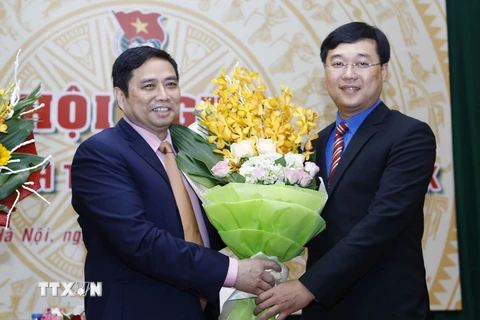 Trưởng Ban Tổ chức Trung ương Phạm Minh Chính (bên trái) tặng hoa chúc mừng tân Bí thư thứ nhất Trung ương Đoàn Lê Quốc Phong. (Ảnh: Phạm Kiên/TTXVN)