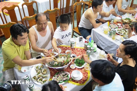 Du khách thưởng thức các món ăn hải sản tại bãi tắm Thiên Cầm. (Ảnh: Phan Quân/TTXVN)