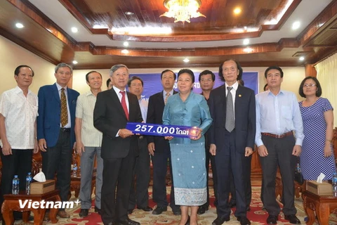 Bà Sunthone Saychac trao số tiền 257.000 USD cho Đại sứ Nguyễn Mạnh Hùng. (Ảnh: Nguyễn Chiến/Vietnam+)