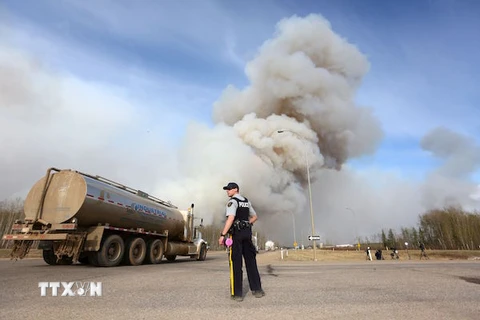 Cảnh sát làm nhiệm vụ tại khu vực đường cao tốc gần đám cháy rừng ở Fort McMurray, Alberta. (Nguồn: AFP/TTXVN)
