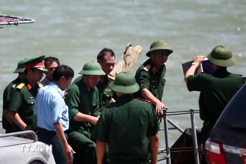 Phi công Nguyễn Hữu Cường (giữa) được tàu biên phòng BP-34-98-01 đưa vào bờ. (Ảnh: Thanh Tùng/TTXVN)