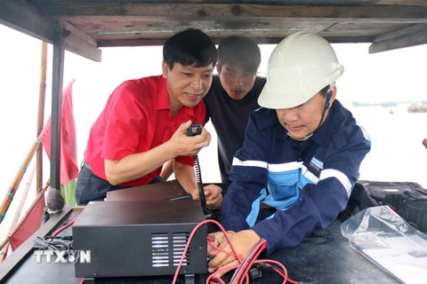 Lắp đặt thiết bị thông tin liên lạc lên tàu cho ngư dân. (Ảnh: Nguyễn Thanh/TTXVN)