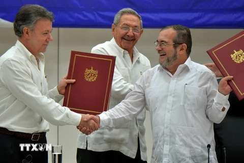 Tổng thống Colombia Juan Manuel Santos (trái) và thủ lĩnh FARC Timoleon Jimenez (phải) trong lễ ký thỏa thuận ngừng bắn vĩnh viễn dưới sự chứng kiến của Chủ tịch Cuba Raul Castro. (Nguồn: AFP/TTXVN)