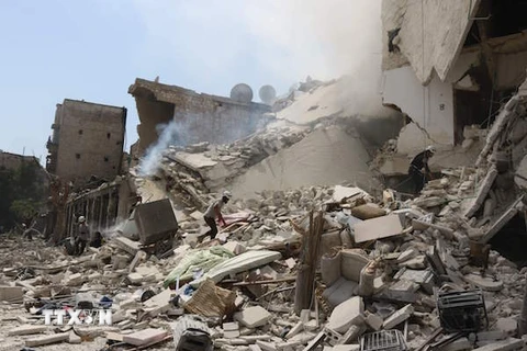 Nhân viên cứu hộ Syria tìm kiếm nạn nhân dưới những đống đổ nát sau vụ không kích tại Aleppo. (Nguồn: AFP/TTXVN)