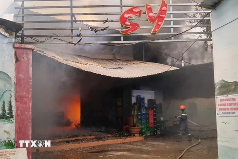 Lực lượng cứu hỏa phải phá tường để phun nước dập ngọn lửa đang bùng cháy bên trong quán karaoke Cosy. (Ảnh: Nam Thái/TTXVN)