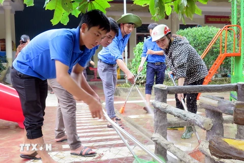 Lực lượng đoàn thanh niên Thạch Hà giúp Trường Mầm non Thạch Đài vệ sinh sân trường. (Ảnh: Công Tường/TTXVN)