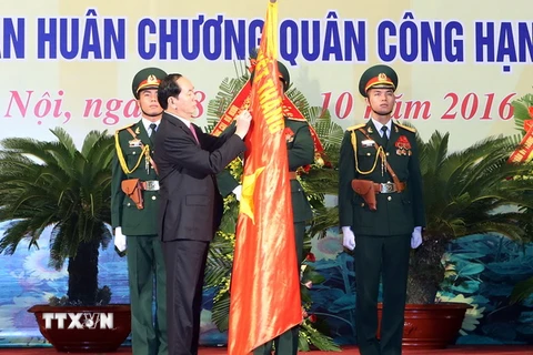 Chủ tịch nước Trần Đại Quang gắn Huân chương Quân công hạng Nhất lên lá cờ truyền thống của lực lượng vũ trang Thủ đô. (Ảnh: Nhan Sáng/TTXVN)