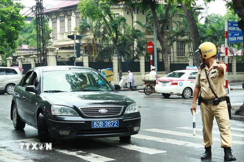 Cảnh sát giao thông ra hiệu lệnh dừng xe biển xanh trên phố Trần Phú, Hà Nội. (Ảnh: Doãn Tấn/TTXVN)