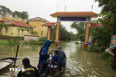 Người dân ở xã Quảng Thọ, huyện Quảng Điền đi lại bằng thuyền. (Ảnh: Hồ Cầu/TTXVN)