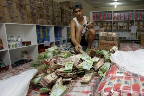 Một người đàn ông đếm những đồng tiền bolivar trong một cửa hàng ở Brazil. (Nguồn: Reuters)