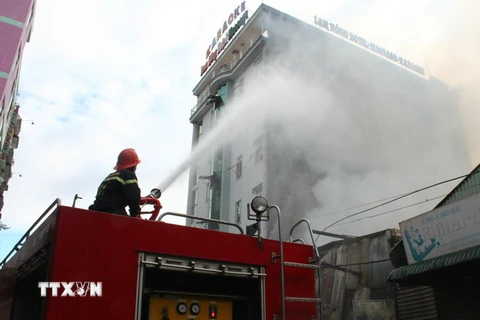 Lực lượng Cảnh sát phòng cháy chữa cháy đang nỗ lực dập lửa ngăn cháy lan sang quán karaoke, khách sạn liền kề. (Ảnh: Sỹ Tuyên/TTXVN)