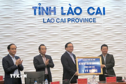 Bí thư Thành ủy Hà Nội Hoàng Trung Hải tặng quà và kinh phí hỗ trợ Quỹ xóa đói giảm nghèo tỉnh Lào Cai. (Ảnh: Hương Thu/TTXVN)