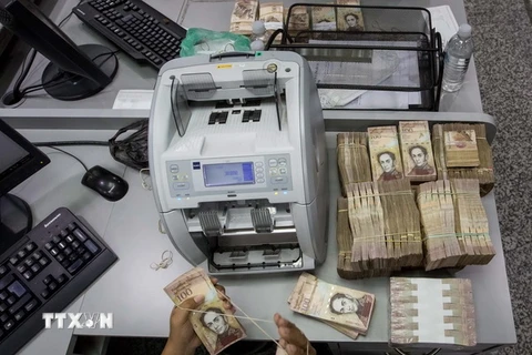 Kiểm tiền mệnh giá 100 Bolivar tại một ngân hàng ở Caracas. (Nguồn: EPA/TTXVN)